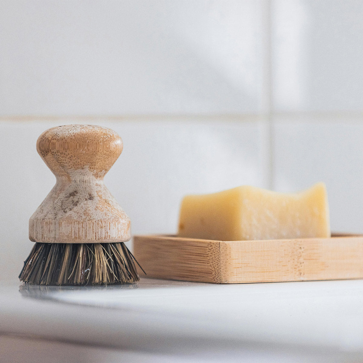 A bar of soap drying on a slatted wooden dish beside a scrub brush