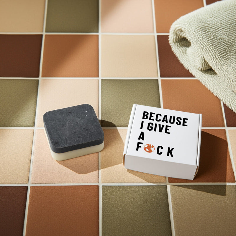 Flatlay of upcycled coffee soap with bold 'Because I Give a F🜃CK' packaging on warm tile – article on upcycling vs skincare